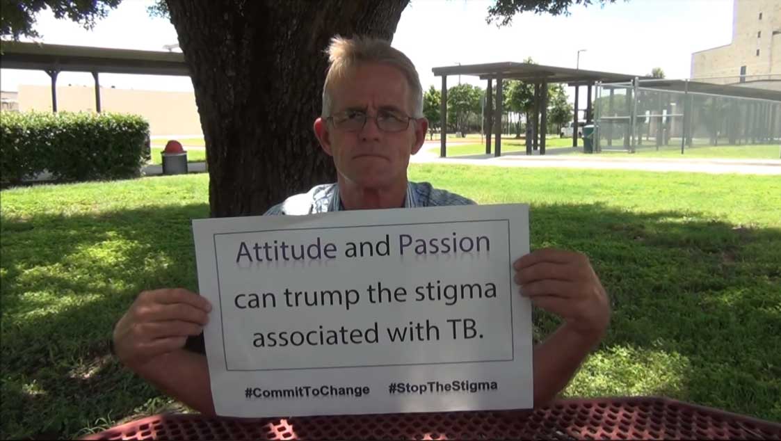 Patient holding up a sign with the text "Attitude and Passion can trump the stigma associated with TB."